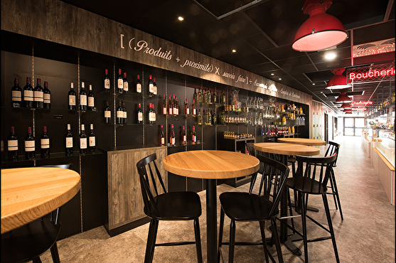 La brasserie possède une cave à vin moderne visible par les clients. Des tables hautes cosy se trouvent devant.