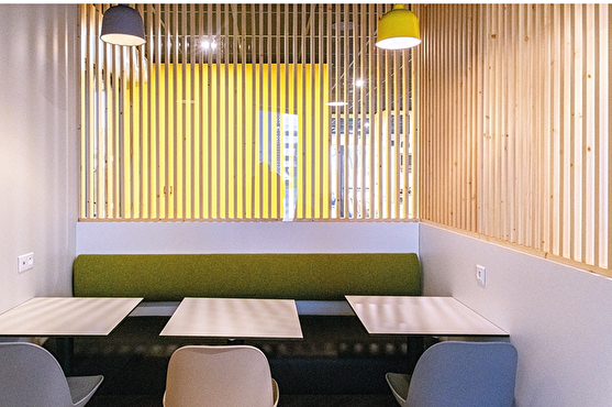 Séparation des espaces : cloisons modernes en bois clair. Assises (banquettes et chaises) modernes, de couleur verte