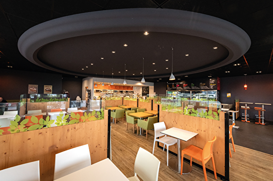 Salle de restaurant design divisée en espaces personnels. Luminaires modernes au plafond