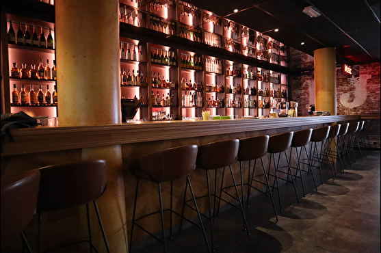 Comptoir et tabouret de bar design, mur lumineux de bouteilles derrière le bar