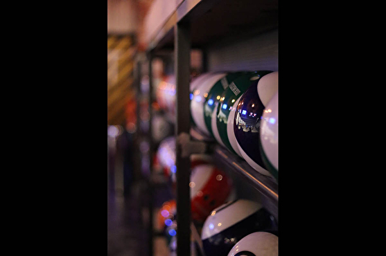 Photographie des boules de bowling rangées dans une étagère métallique