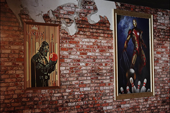 Le mur effet brique est décoré avec des images de Super Héros jouant au bowling