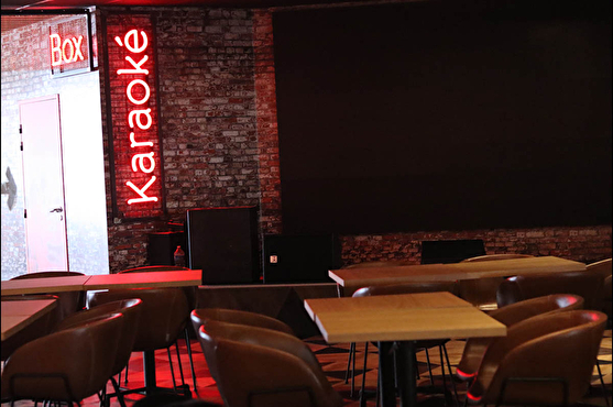 Le salle principale est composée d'une partie restaurant avec des tables et chaises modernes et les autres espaces sont indiqués par des néons rouges (karaoké)