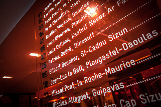 La liste des producteurs travaillant pour le restaurant est affichée sur un mur orange et vitré.
