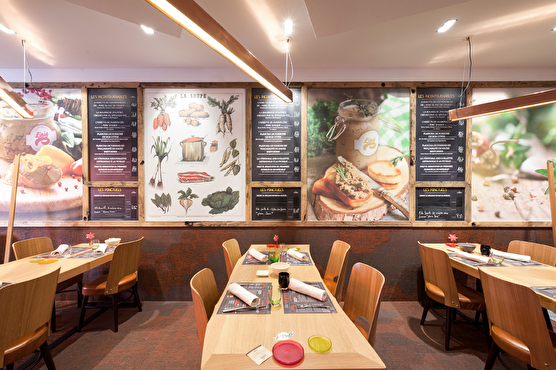Chaque table en bois est illuminée par un long néon blanc et le mur est couvert par les menus ainsi que des photographies de plats bien présentés