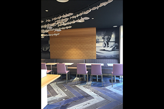 Le sol du restaurant donne un effet parquet de couleur bleu marine, bleu plus clair et gris. Des panneaux de bois habillent les murs.