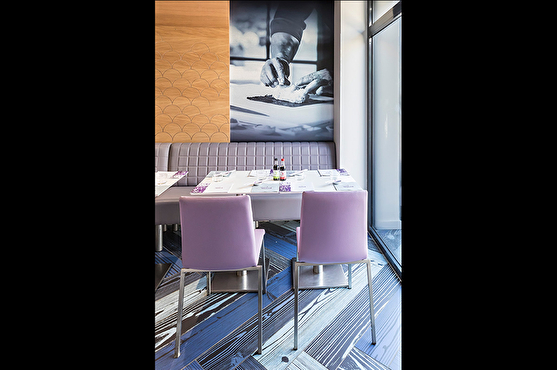 Le long du mur, les clients peuvent s'asseoir à table sur une longue banquette grise ou sur des chaises roses.