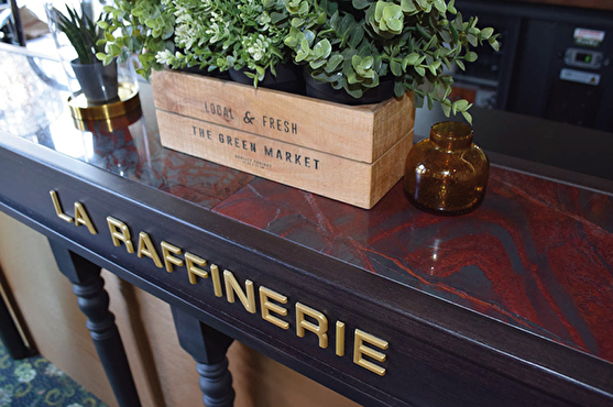 Le comptoir rétro de La Raffinerie est rouge et marron et le nom du restaurant y est inscrit en lettres d'or.
