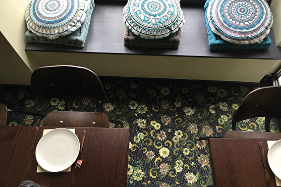 La moquette à motif floral apporte de la couleur qui contraste avec le dressage simple des tables.