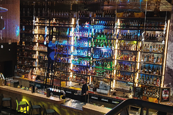 Décoration bar : mur de bouteilles de 6m de haut et jeux de lumière