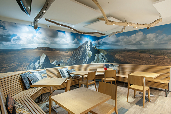 Aménagement d'un espace où s'asseoir à table. Banquettes en bois et décoration panoramique des Mont d'Arrée
